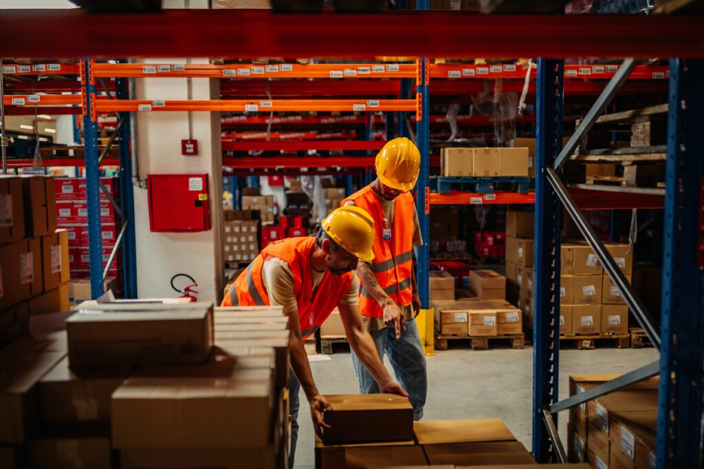 Workers in warehouse with safety helmets stacks the boxes