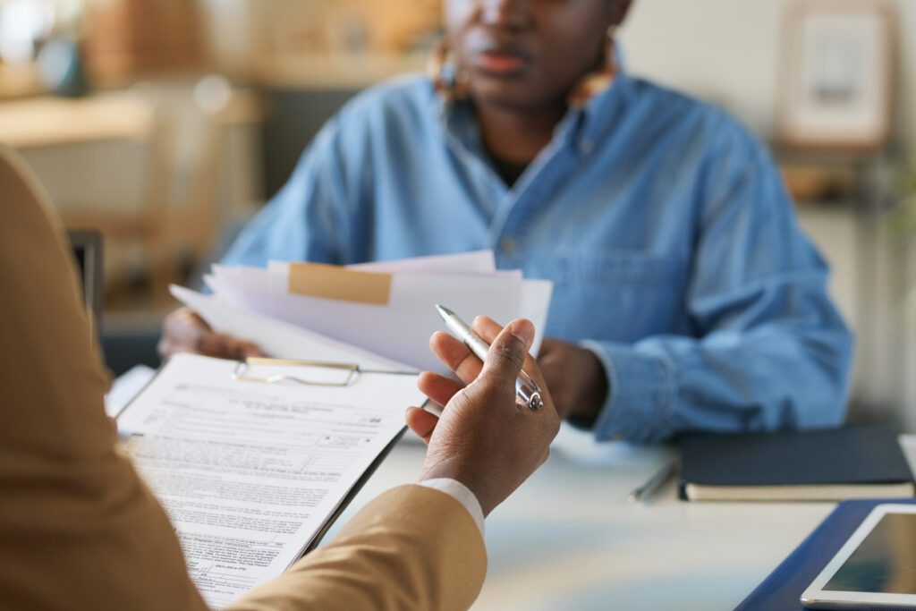 Close up of unrecognizable African American man holding documents and pointing with pen while discussing taxes and finances with wife at home copy space