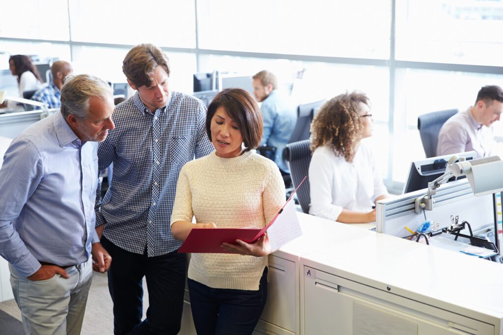 Casually dressed staff standing in a busy open plan office
