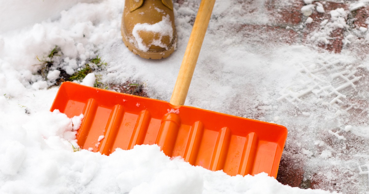 Person in boots shovels snow with a snow shovel