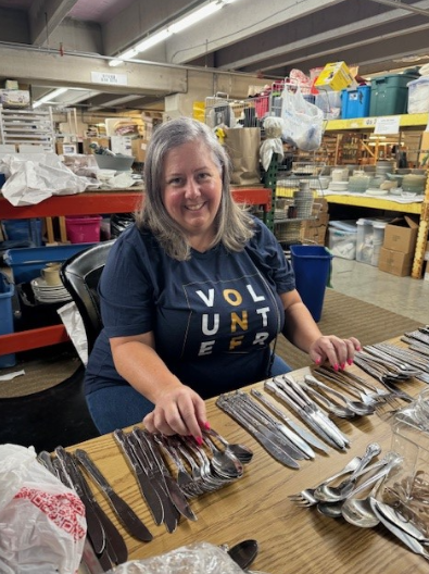 Employee organizes silverware at a table.